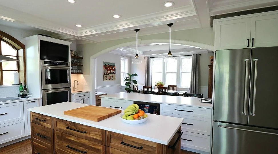 Bright white kitchen with walnut island, arched doorway and stainless refrigerator
