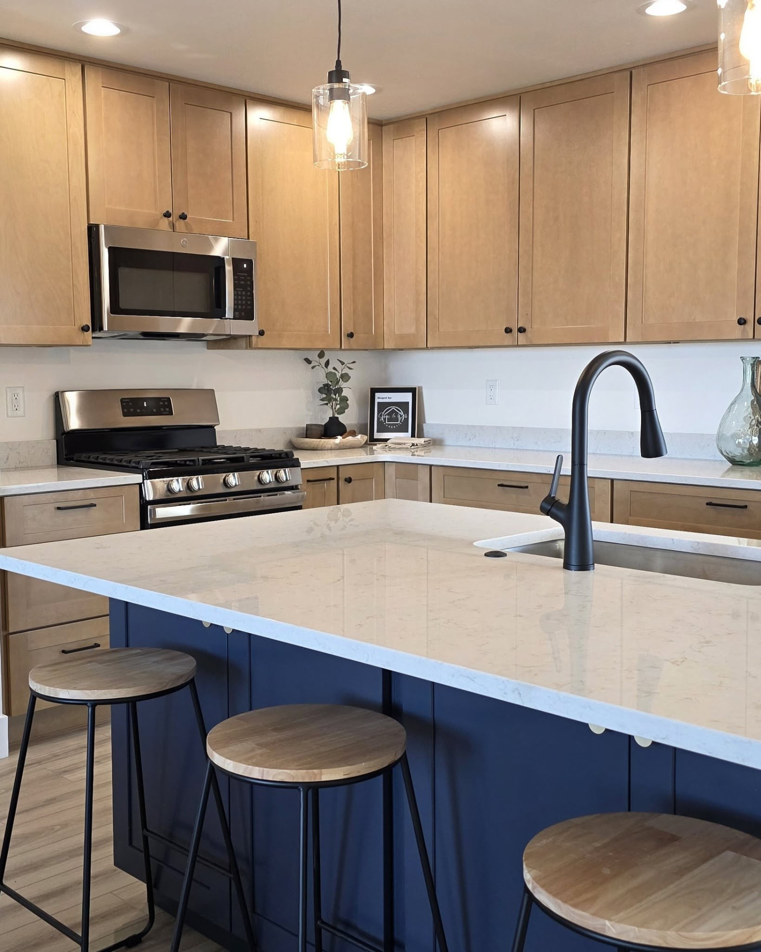 Remodeled kitchen with light wood cabinets, a navy island and white quartz countertop